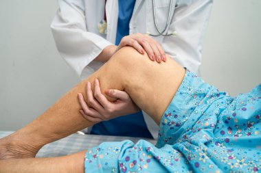 Hastanede, Asyalı yaşlı kadın diz protezi ameliyatını kontrol eden bir doktor..