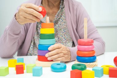 Bunama geçiren Asyalı yaşlı kadın hasta pratik motor beceri rehabilitasyonu öğreniyor.