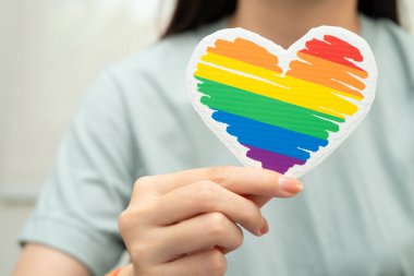 Gökkuşağı bilekliği takan Asyalı kadın ve kırmızı kalp, LGBT onur ayının sembolü, Haziran sosyal ortamında eşcinsel, lezbiyen, biseksüel, transseksüel, insan hakları kutlamaları.