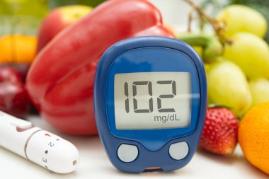 Asya 'da el ele tutuşan dijital glikoz monitörü sebze ve meyveli sağlıklı gıda ölçümü.