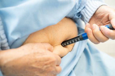 Kıdemli kadın hasta diyabet tedavisi için insülin enjekte ediyor..