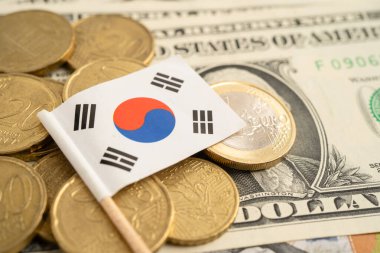 İçinde Güney Kore bayrağı ve Amerikan doları banknotları olan bozuk para yığını..