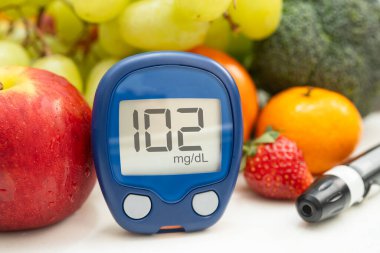Asya 'da el ele tutuşan dijital glikoz monitörü sebze ve meyveli sağlıklı gıda ölçümü.