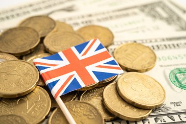 Birleşik Krallık bayrağı ve Amerikan doları banknotları olan bozuk para yığını.