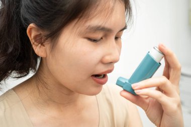 Astım ve kronik obstrüktif akciğer hastalığı COPD, ölçülü doz solunum cihazı kullanan Asyalı kadın..