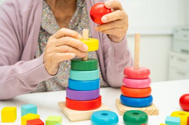 Bunama geçiren Asyalı yaşlı kadın hasta pratik motor beceri rehabilitasyonu öğreniyor.