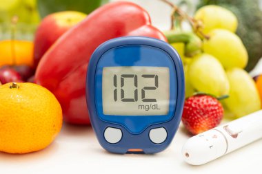 Asya 'da el ele tutuşan dijital glikoz monitörü sebze ve meyveli sağlıklı gıda ölçümü.