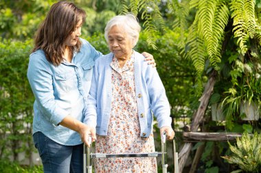 Bakıcı yardım ve bakım Asyalı son sınıf öğrencisi kadın Walker 'la parkta yürüyor..