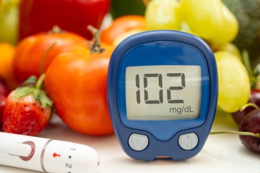 Asya 'da el ele tutuşan dijital glikoz monitörü sebze ve meyveli sağlıklı gıda ölçümü.