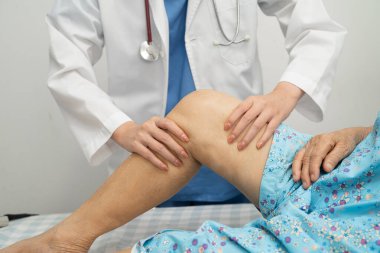 Hastanede, Asyalı yaşlı kadın diz protezi ameliyatını kontrol eden bir doktor..