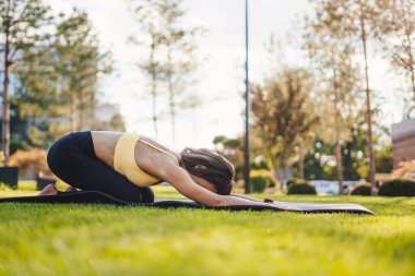Rahat giyimli, dinlenme egzersizi yapan ve belini esneten bir kadının yan görüntüsü. Açık hava yaşam tarzı. Sağlıklı yaşam tarzı, spor
