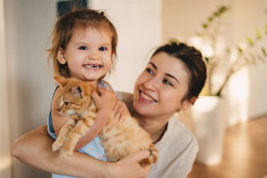 Evde, oturma odasında kedileriyle oynarken mutlu aile zamanları dilerim. Mutlu aile, çocukluk. Gülümse. Ebeveyn, çocuk. İnsanların yaşam tarzı. Eğlenceli.