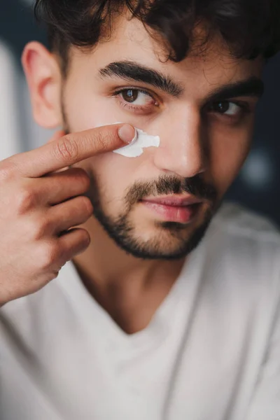 Widok Mężczyzny Nakładającego Krem Kosmetyczny Policzek Robiącego Poranną Rutynę Portret — Zdjęcie stockowe