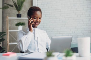 Gülümseyen müşteri hizmetleri temsilcisi ofisinde iş telefonu görüşmesi yapıyor. Cep telefonu iletişimi. İnsanların yaşam tarzı. Bağımsız