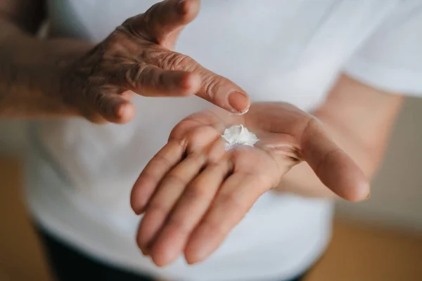 stock image Selective focusing moisturising lotion cream on senior woman hands. Closeup portrait. Beauty treatment. Skin care. Medical healthcare.