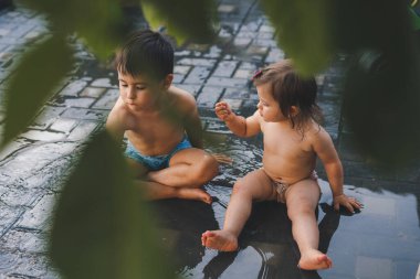 Mutlu komik iki çocuk yağmurun tadını çıkarıyor, doğada oynuyorlar. Yaz doğası. Küçük bahçe. Mutluluk kavramı.
