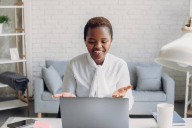 Mutlu Afro-Amerikan kadın serbest yazar, iş arkadaşlarıyla çevrimiçi bir görüşme yaparken görüntülü konuşuyor. Evde internet konferansı yapan bir kadın.