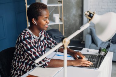 Ofiste dizüstü bilgisayar kullanan genç Afro-Amerikalı bir iş kadını internet kamerasından görüntülü arama yapıyor. İnsanların yaşam tarzı. İş toplantısı. Web toplantısı. Çevrimiçi
