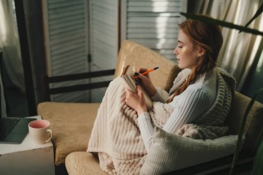 Evde göz bandı takan hoş bir bayan dinlenirken bir günlüğe notlar yazıyor, ev hayatının tadını çıkarıyor. Dinlenme, tatil, güzellik tedavisi
