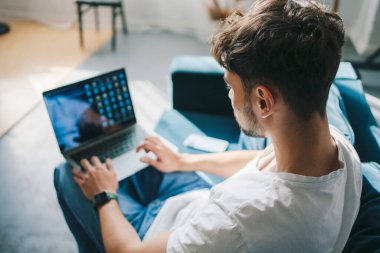 Bir iş adamının kanepeye oturup evdeki laptopuyla sabah haberlerini okuması, evden çalışması. Günlük iş adamı ya da serbest çalışan rahatlamış
