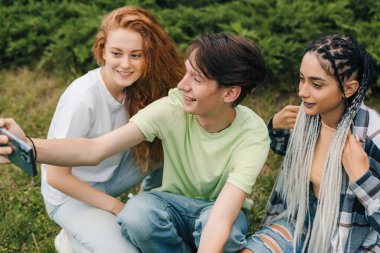 Genç bir çocuk ve arkadaşları gün batımında parkta akıllı telefon kamerasıyla videolarını hazırlıyorlar. Videoyu sosyal medya uygulamasına paylaşmak için. Cep telefonu