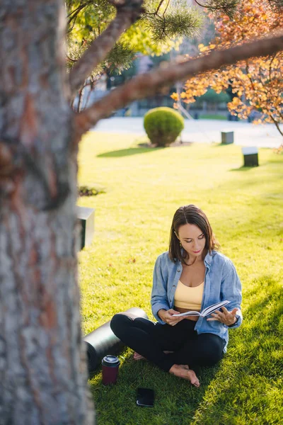 Atrakcyjna Sportowa Kobieta Siedząca Trawie Pod Drzewem Parku Czytająca Książkę — Zdjęcie stockowe