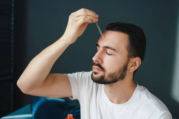 Ung Man Applicerar Organiskt Serum Ansiktet Med Pipett Skönhetsbehandling Kosmetisk — Stockfoto