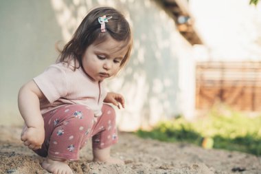 Bahçedeki kumlu toprakta oynayan sevimli kızın portresi. Uzayı kopyala Yaz tatili eğlencesi. Doğa yazı. Yazın açık hava eğlencesi.