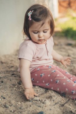 Beyaz, şirin bir kız çocuğu yazlık evin bahçesinde kumla oynuyor. Yazın açık hava eğlencesi. Tasasız çocukluk. Küçük bahçe. Sağlıklı aktivite. Güneşli bir gün