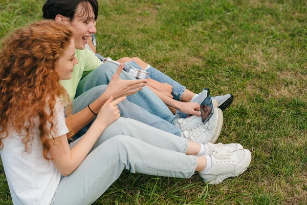 부주의 친구들은 스마트폰 화면을 보면서 비디오 블로그를 녹화하고 야외의 풀밭에 — 스톡 사진