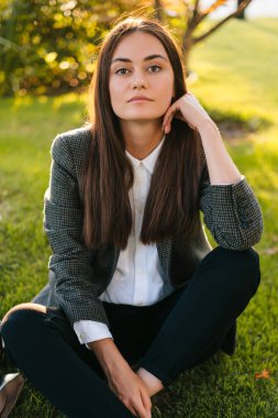 Başarılı bir kadın serbest çalışanın yeşil çimlerde oturup açık havada işe ara verişi. Açık havada materyali öğrenme ve öğrenme kavramı