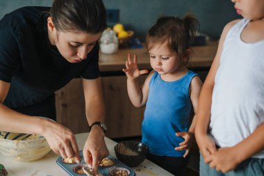 Anne ve küçük çocukları mutfakta çörekleri silikon kalıbın içine dolduruyorlar. Şekerleme pişirme kavramı. Kek, turta, bisküvi yapmak için adım