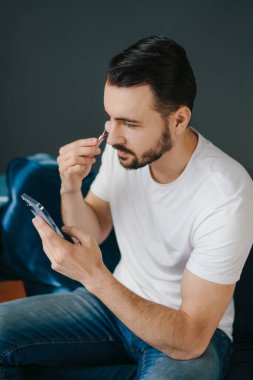 Adam akıllı telefon ekranına bakarken evde yeşim taşıyla yüz gerdirme ameliyatı yapıyor. Dermatoloji, kozmetoloji. Vücut bakımı. Tutan adam