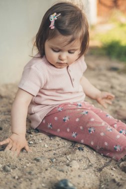 Küçük kız bebek evin avlusunda kumla coşkuyla oynuyor. İnsanların yaşam tarzı. Mutlu bir aile. Arkadaşlar oynar.