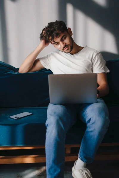 Jovem Usando Laptop Sentado Sofá Azul Casa Descansando Relaxando Enquanto — Fotografia de Stock