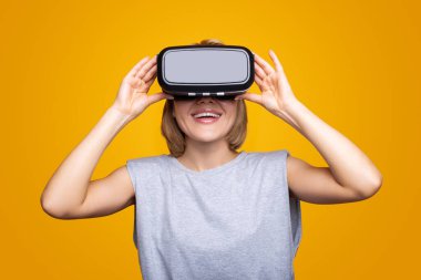 Gülümseyen mutlu beyaz kadın sarı arka planda izole edilmiş VR kulaklık kullanarak deneyim kazanıyor. Modern 3d. Modern teknoloji. Video oyunu arkaplanı