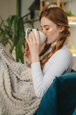 Neşeli güzel bir kadının portresi rahatlatıcı, sıcak bir fincan kahve içen evde tatilin tadını çıkaran. Rahat bir hafta sonu tatili. Soğuk kış