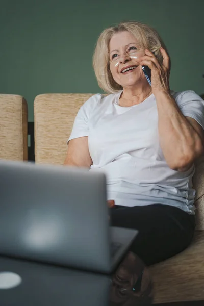 stock image Happy old mature retired woman relaxing alone on cozy sofa, enjoying a conversation on her mobile phone spending weekend time alone at home. Elderly generation