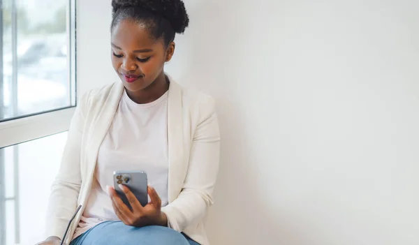 stock image Beautiful happy business african woman with a phone in her hands sitting in a cafe drinking an ice coffee. Girl rest and working in a cafe