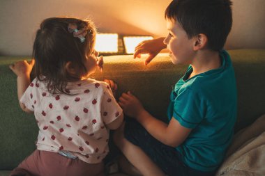 Erkek ve kız kardeş kanepede birlikte oynuyorlar, eğleniyorlar. İnsanların yaşam tarzı. Mutlu bir yaşam tarzı. Mutlu aile.