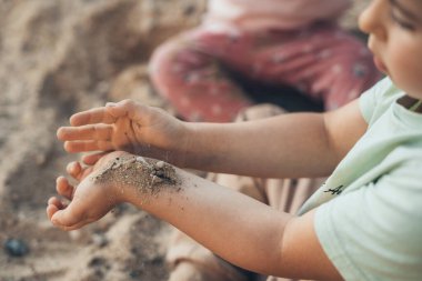 Close-up view of boys hands with sand from the garden. Summer vacation concept. Summer vacation fun. Outdoor fun.