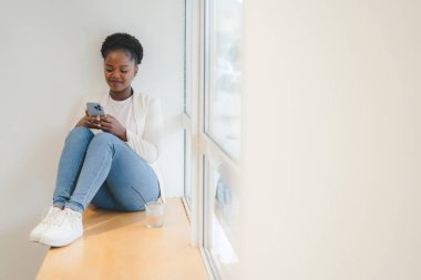 Young pretty woman using smartphone, touch screen while having breakfast in the cafe. Woman surfing internet. Internet technology.