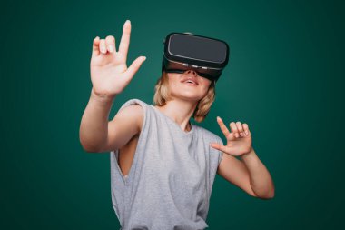 Gamer female student in VR headset exploring educational videogame and learning about science, isolated over green background.