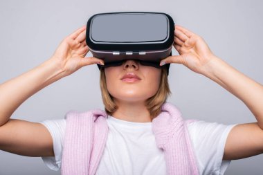 Front view portrait of a charming blonde-haired woman wearing VR glasses on white background. Innovative technologies. Game industry.