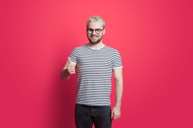 Man wearing eyeglasses isolated over pink background doing thumbs up gesture with hand. Approving expression looking at the camera with showing success.