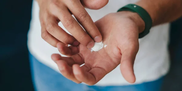 Close-up of man hands holding white cream on forefinger. Taking care of your skin.