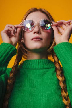 Fashionable attractive woman wearing sunglasses, trendy, posing on yellow background. Trendy style. Attractive beautiful girl.