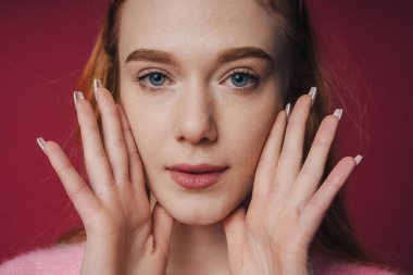 Beautiful young caucasian woman with clean fresh skin isolated on red background. Face care. Facial treatment. Cosmetology, beauty and spa.