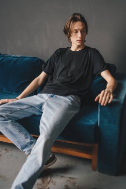 Calm millennial man sitting on comfy sofa in relaxed pose resting from hard working day. People lifestyle. Modern lifestyle. Happy lifestyle.