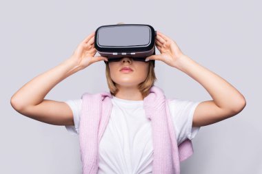 Portrait of young woman playing VR game wearing VR headset, half body shot. Young generation choose virtual reality relaxation concept.